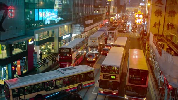 Στο Χονγκ Κονγκ. Κίνα-περίπου Ιαν 2015: τα λεωφορεία μπλοκάρουν προσωρινά την πολυσύχναστη νυχτερινή κυκλοφορία σε ένα μεγάλο δρόμο της πόλης στο κέντρο του Χονγκ Κονγκ. από πάνω. — Αρχείο Βίντεο