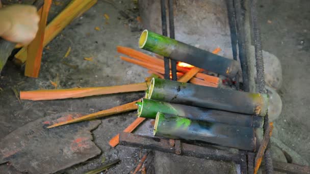 Aziatische Artisan drogen bamboe buizen over een brand — Stockvideo