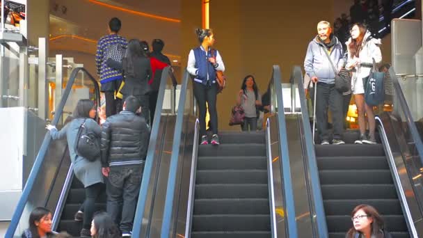 Multidões de pedestres subindo e descendo um triplo largo banco de escadas rolantes em um centro comercial no centro de Hong Kong . — Vídeo de Stock