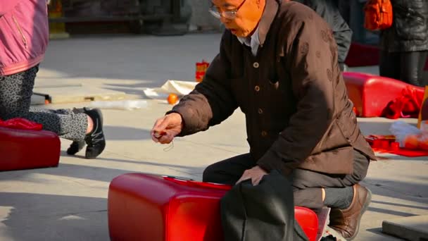 Elderly buddhist worshipper bowing and praying on a cushion before an alter at Wong Tai Sin Temple in Hong Kong. — Stock Video