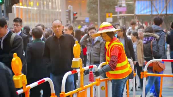 Une travailleuse de la construction portant un chapeau de paille à large bord et un gilet de sécurité orrange ajuste une barrière de circulation sur un site à Hong Kong . — Video