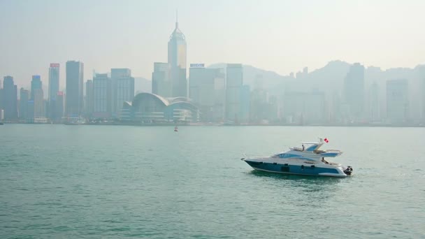 Petite. yacht privé croisières lentement dans le port de Victoria avec Downtown Hong Kong moderne skyline en arrière-plan . — Video