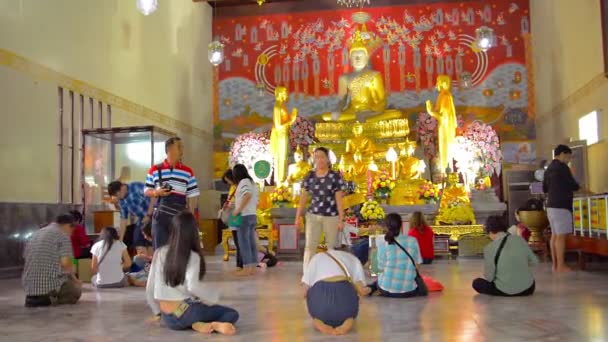 Buddhist worshippers kneel and pray before a gilded image of the Buddha at a temple inside Ayutthaya Historical Park in Thailand. — Stock Video