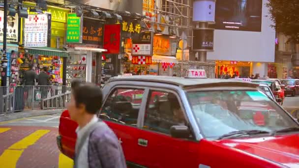 Långa raden av röda och vita taxibilar väntar på passagerare på ett livligt shoppingområde i Downtown Hong Kong. — Stockvideo