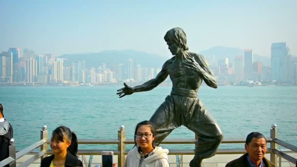 Туристы позируют для фотографий и селфи перед бронзовой статуей Брюса Ли возле набережной Цим Ша Цуй . — стоковое видео