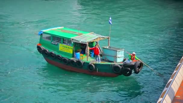 Dolgozók egy kis közüzemi hajó sovány szemetet és törmeléket a felszínről a víz a kikötőben. — Stock videók