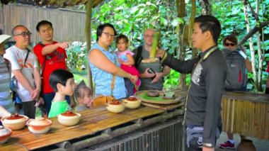 Tur rehberi geleneksel açıklayan. Kota Kinabalu yakınlarındaki bir köyde turistlere yerli ürünler.