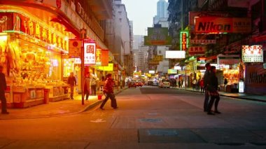 Akşam ın erken saatlerinde Hong Kong şehir merkezindeki yoğun bir alışveriş bölgesinin sokaklarında aşağı yukarı dolaşan alışverişçiler.