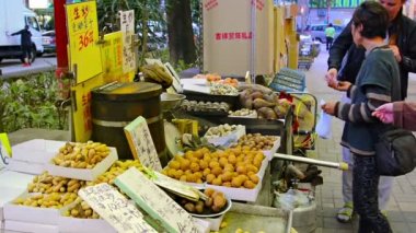 Yerel sokak gıda satıcısı pişirme ve kestane satan. hong kong şehir merkezinde bir mobil sepeti tatlı patates ve diğer kavrulmuş aperatifler.