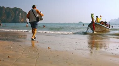 Bavulunu bir tur teknesine taşıyan turist. sığ lıklarda bekliyor. Tayland'daki güzel Railay Plajı'nın hemen dışında. Güneydoğu Asya.