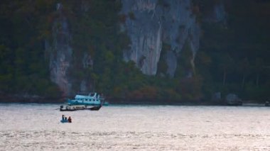 Tayland Phi Phi Adası'nda yükselen kayalıkların altında koyda seyir küçük tur teknesi. Güneydoğu Asya.