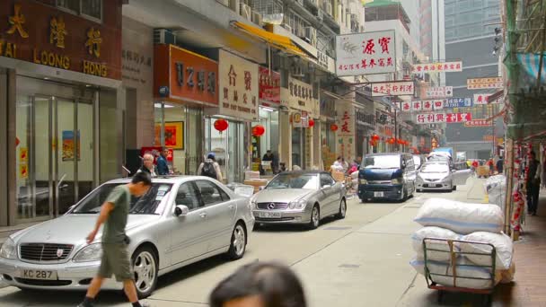 Einkäufer und Kunden flanieren zwischen den Geschäften entlang einer belebten Geschäftsstraße in der Innenstadt von Hongkong. — Stockvideo