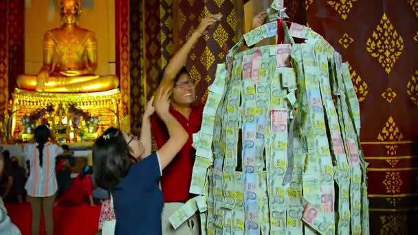 Buddhistische Gläubige heften Papiergeld als Opfergabe in einem Tempel im Ayutthaya historischen Park in Thailand an einen Drahtgestell. — Stockvideo