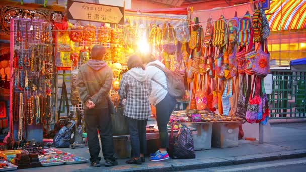 Los clientes que navegan por una tienda de artículos en un puesto en el mercado de Jade en Kansu Street están ocupados. centro de Hong Kong . — Vídeo de stock