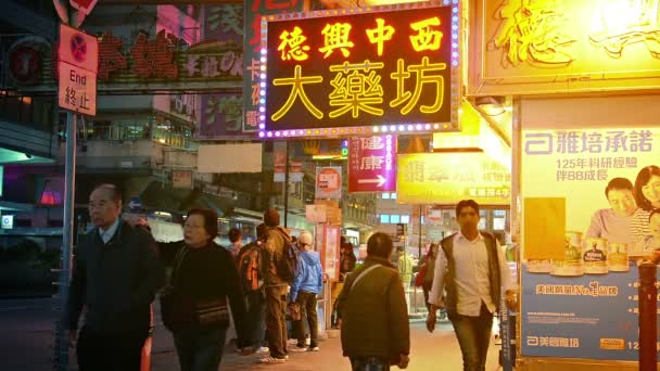 Pesado tráfico nocturno a pie en una acera del centro en un concurrido distrito comercial de Hong Kong . — Vídeos de Stock