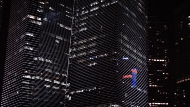 Panning shot of big. contemporary. angular. highrise office buildings at night. with backlit windows — Stock Video