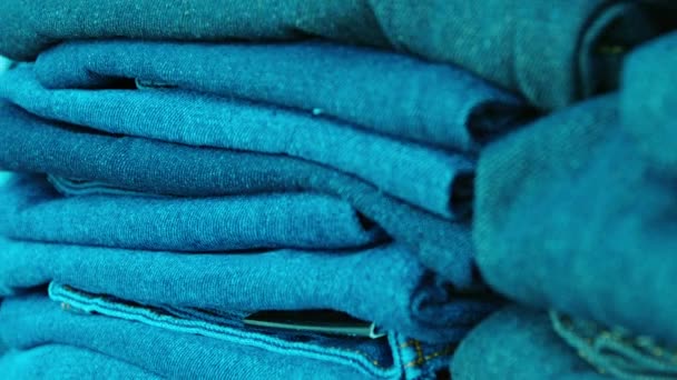 Many pairs of denim blue trousers. folded and neatly stacked in a public market. — Stock Video