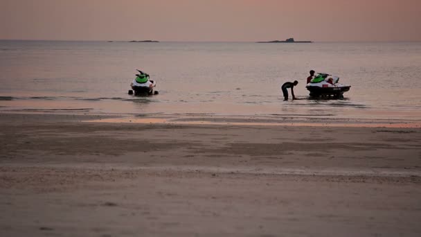 Trabajadores que transportan jetskis de alquiler fuera del agua en los remolques al final del día en esta popular playa turística — Vídeos de Stock