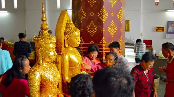 Οι βουδιστές πιέζουν το χρυσό φύλλο σε αγάλματα του Βούδα ως προσφορά πριν από την προσευχή σε ένα ναό στην Αγιουτάγια. Ταϊλάνδη. — Αρχείο Βίντεο