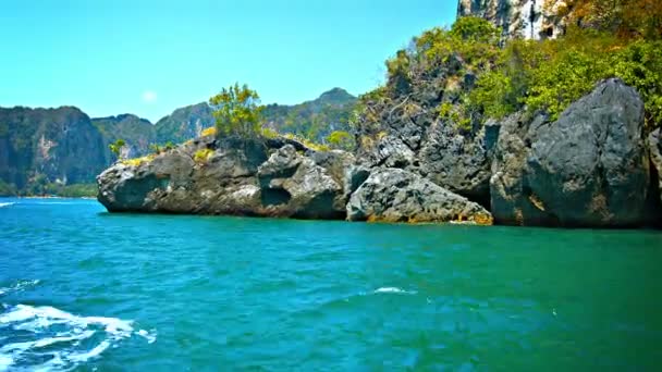 Handgemaakte. houten Tour boot cruisen langs een ruige. rotsachtige kustlijn. op een terugreis van Railay Beach. Thailand. op de achtergrond. — Stockvideo