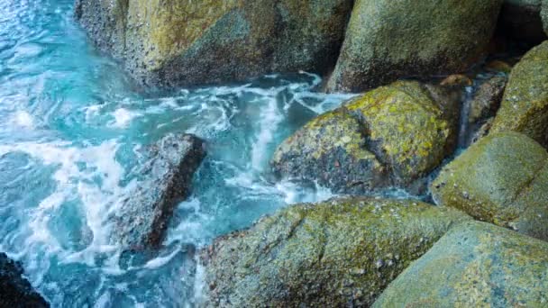 Klares Wasser schwappt auf große bemooste Felsen — Stockvideo