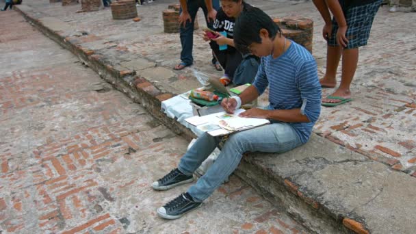 Ayutthaya. Thailand - ca. Feb 2015: lokale Künstler sitzen auf einer Stufe und malen am wat yai chai mongkhon in Thailand. — Stockvideo