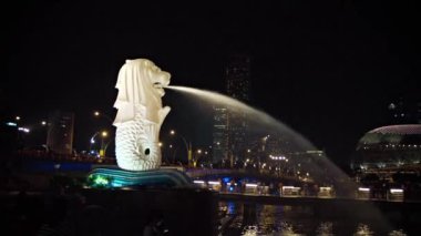 Önemli ölçüde yanan Merlion çeşme. Marina Bay içine su sürekli sprey ile. Singapur'un içinde belgili tanımlık geçmiş ile gece manzarası