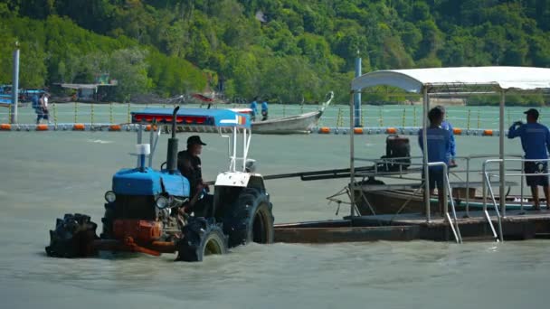 Reiseleiter. Entladen der Ladung von einem handgefertigten. Ausflugsboot aus Holz. auf einen Anhänger, der von einem landwirtschaftlichen Traktor gezogen wurde. im flachen Wasser geparkt. — Stockvideo