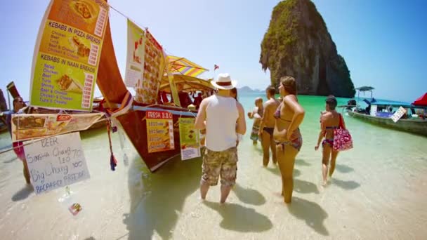 Місцевого постачальника, представляючи розробити вибір смачних продуктів від його ручної роботи дерев'яних човнах на пляж Рейлей в Таїланді. — стокове відео