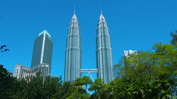 Iconic Petronas Twin Towers. standing against a clear blue sky. as seen from Kuala Lumpur City Centre Park. in Malaysia's capital city. — Stock Video