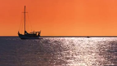 Yelkenli çapa bir turuncu günbatımı gökyüzü altında at binme