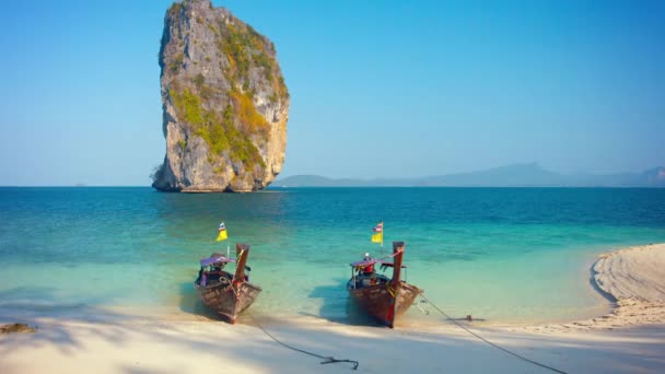 Par de hecho a mano. Barcos de cola larga de madera estacionados debajo de una enorme formación de piedra caliza en Railay Beach en Tailandia — Vídeo de stock