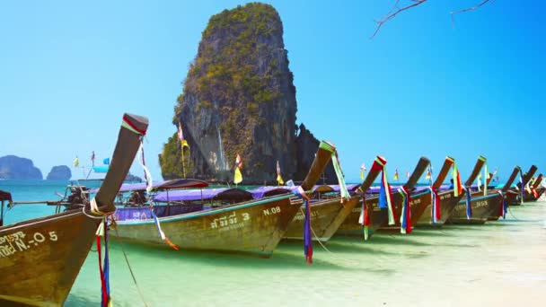 Dlouhá řada Longtail lodě zaparkován na Railay Beach v Thajsku. s velké vápencové formace tyčící se v pozadí — Stock video