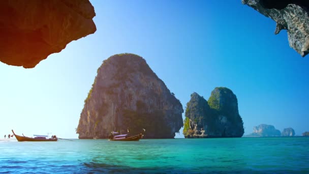 Barco de cola larga acercándose a la desembocadura de una cueva natural cerca de Railay Beach en Tailandia . — Vídeos de Stock