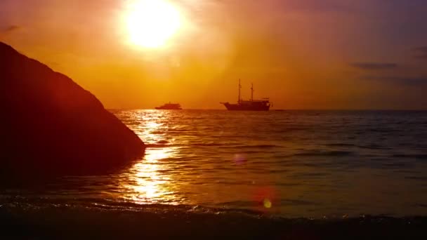 Zonsondergang zeegezicht met golven en boten onder een rode hemel — Stockvideo