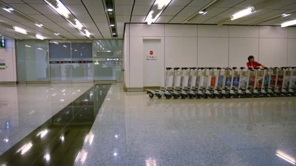 Pessoal do aeroporto usando um motorizado. trator robótico para mover carrinhos de bagagem através de um terminal de passageiros vazio no Aeroporto Internacional de Hong Kong . — Vídeo de Stock