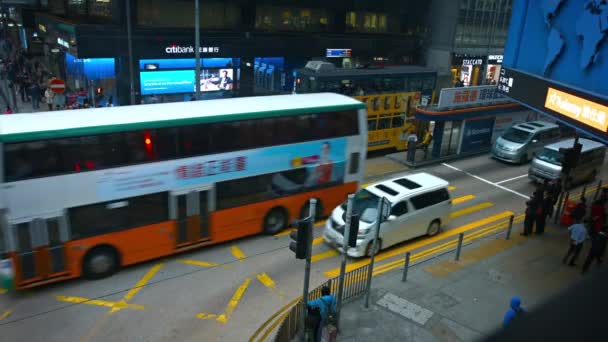 Taxis. busses and electric cable cars crossing through a busy urban intersection in downtown Hong Kong at night. — Stock Video