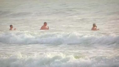 Phuket'teki Kamala Plajı'nda sörf te yüzen turistler. Güney Tayland.