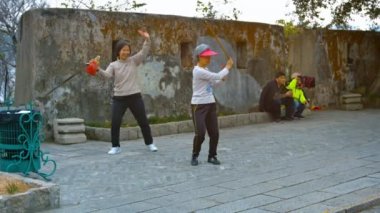 Kadınlar Tai Chi eğitimine Macau 'daki bir şehir parkında silahlarla katılıyorlar.