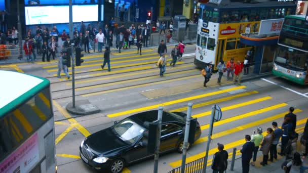 Skara av fotgängare korsar en trafikerad urban gata i Hong Kong — Stockvideo