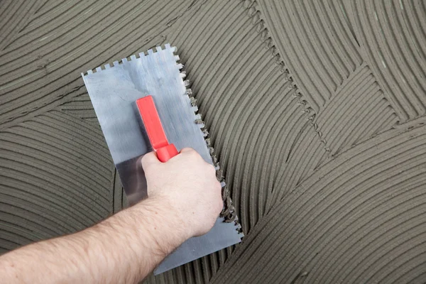 The worker applies glue for a tile on a wall — Stock Photo, Image