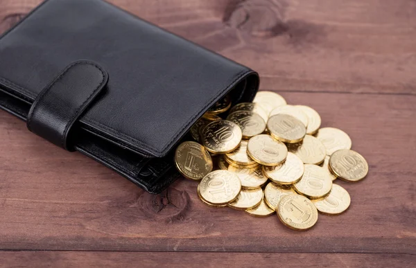 Zwarte lederen portefeuille met gouden munten op hout achtergrond — Stockfoto