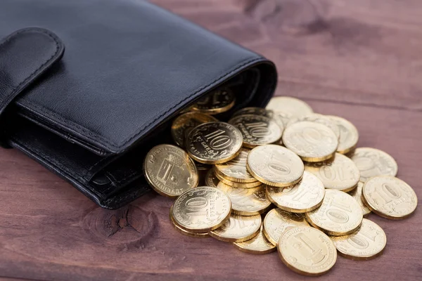 Черный кожаный бумажник с золотыми монетами на деревянном фоне — стоковое фото