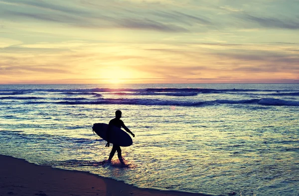 Surfer walking on the beach at sunset — Stock Photo, Image