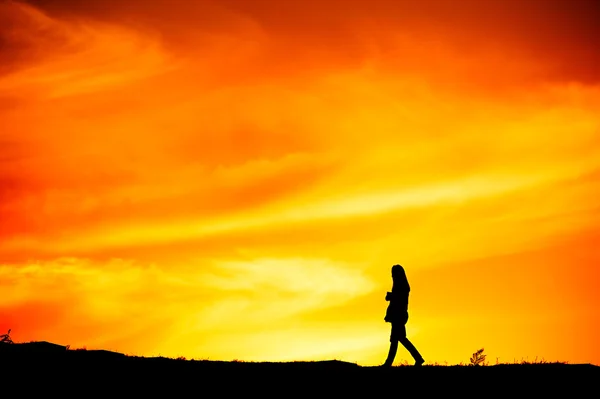 Silhouette einer Frau, die bei Sonnenuntergang geht — Stockfoto