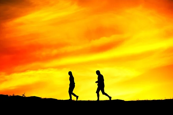 Woman and man walking at sunset — Stock Photo, Image