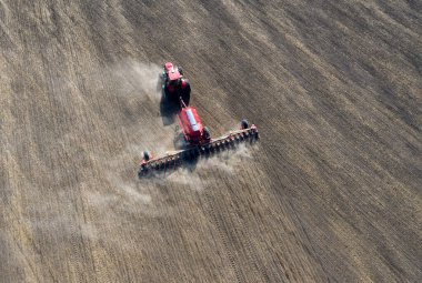 Traktördeki bir çiftçi, tarım sezonunun başında tarım arazisinde ekilen ekin işlerinin bir parçası olarak ekiciyle toprağı hazırlıyor..