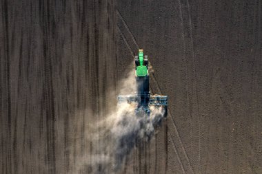 Traktördeki bir çiftçi, tarım sezonunun başında tarım arazisinde ekilen ekin işlerinin bir parçası olarak ekiciyle toprağı hazırlıyor..
