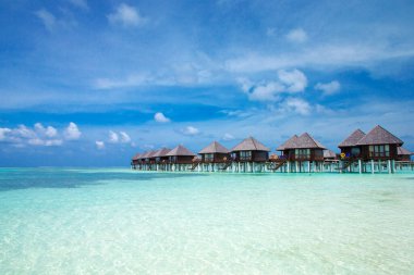 Plajı olan güzel tropik Maldivler adası. Su bungalovları olan deniz.