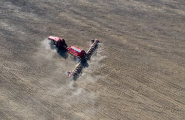 Traktördeki bir çiftçi, tarım sezonunun başında tarım arazisinde ekilen ekin işlerinin bir parçası olarak ekiciyle toprağı hazırlıyor..
